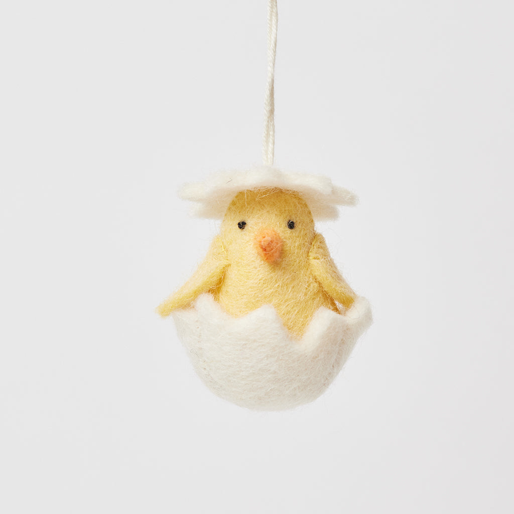 Ornement de poussin éclos dans une coquille blanche